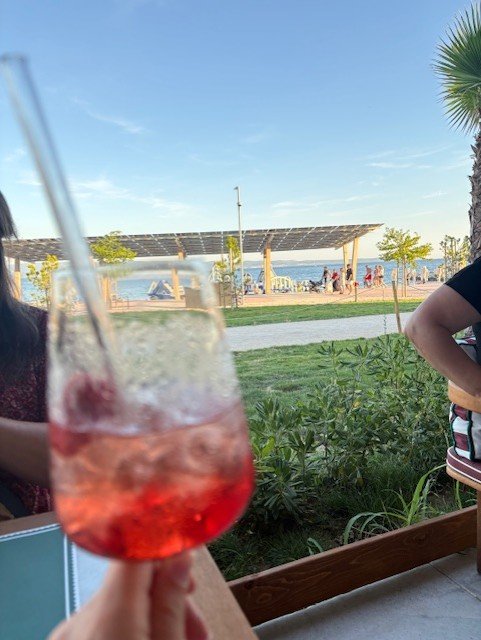 Un verre de spritz en terrasse, face à une plage animée